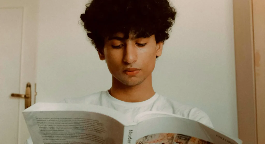 imagen de un chico leyendo un libro con el pelo curly
